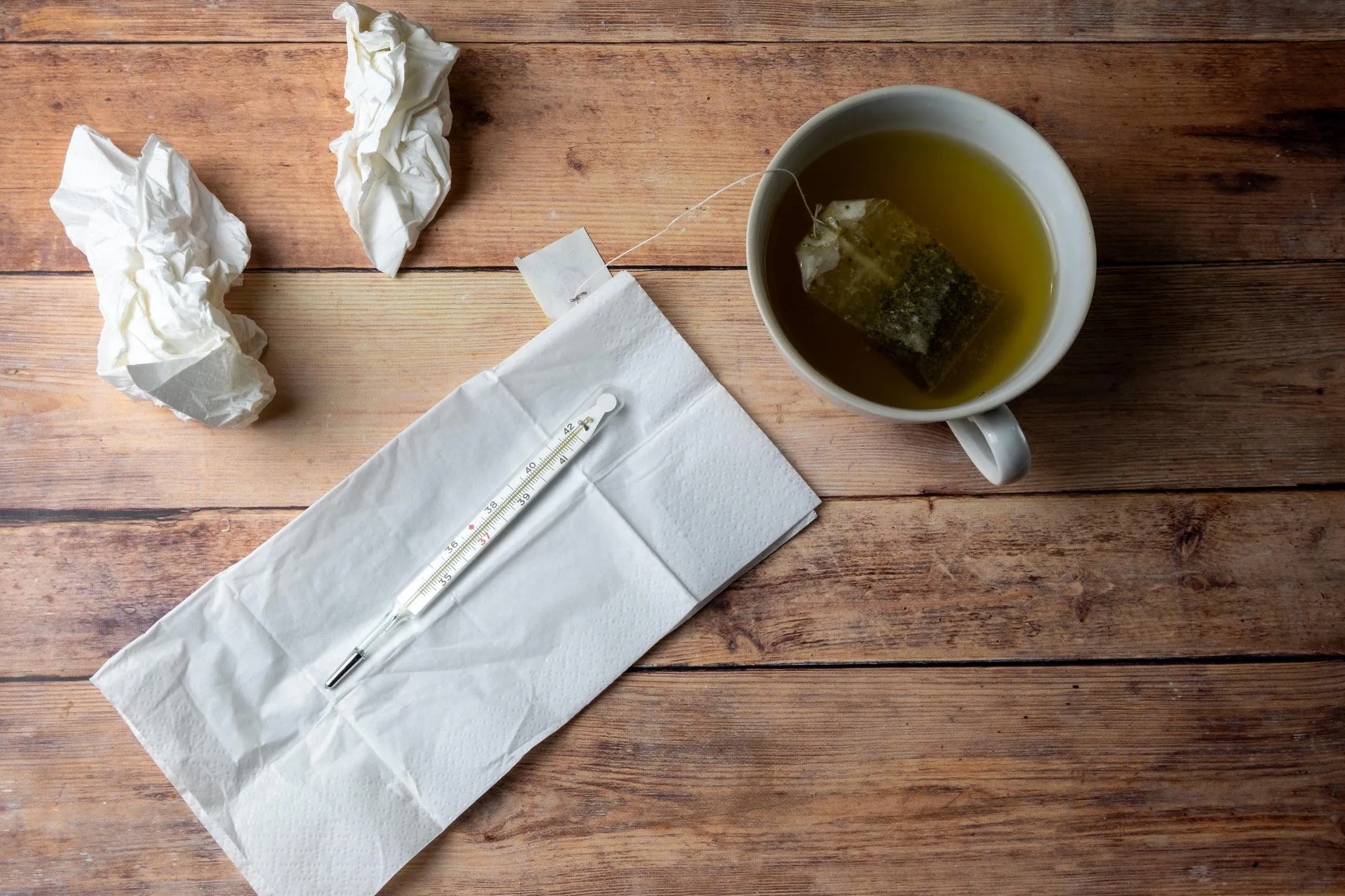 Home care for a sore throat: tea, tissues and a thermometer on a table